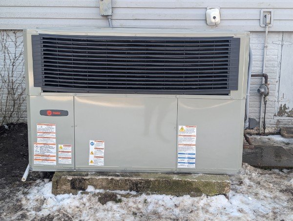 Packaged outdoor heating and cooling system beside a home